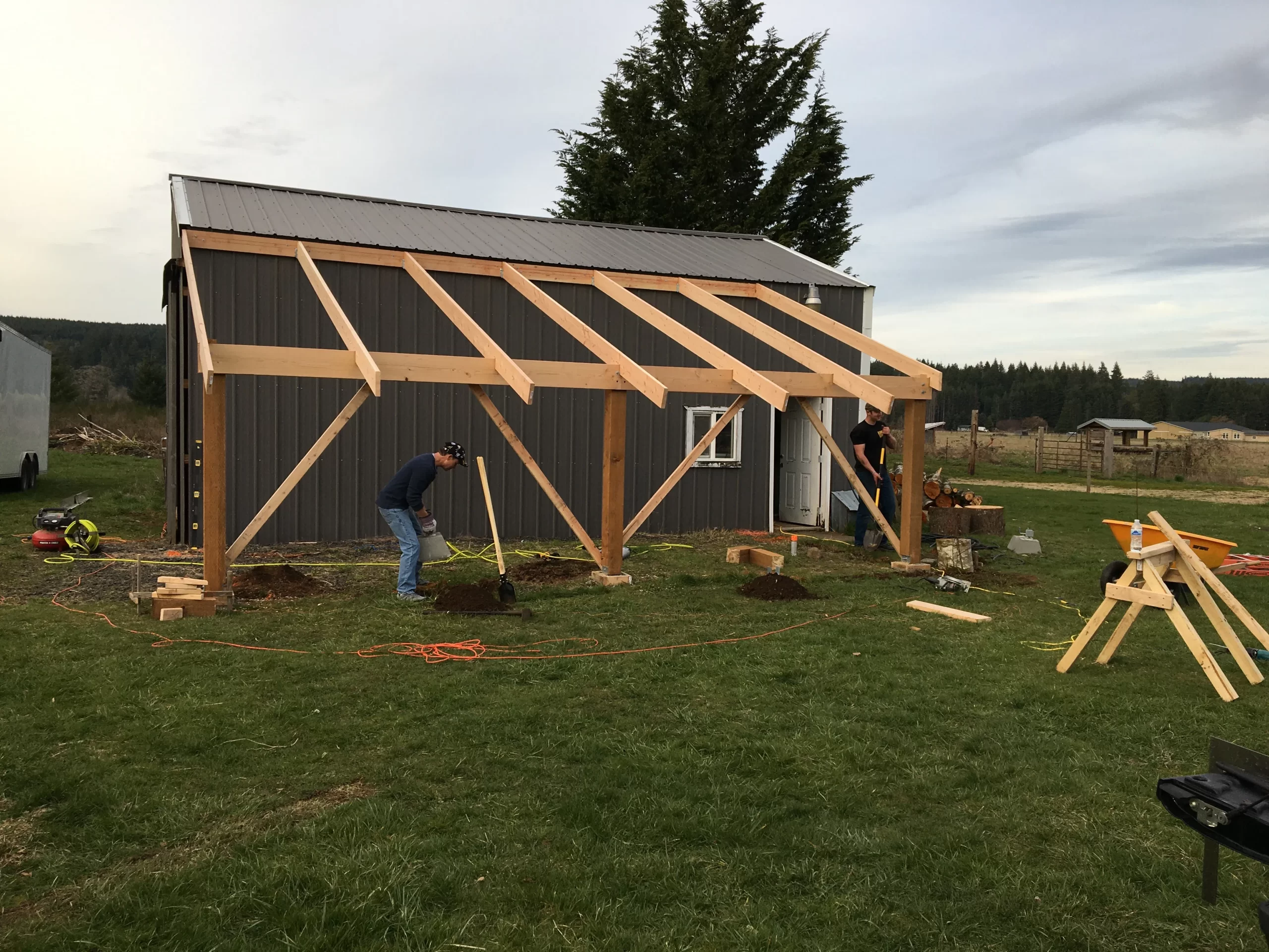 Men constructing wooden extension on rural shed